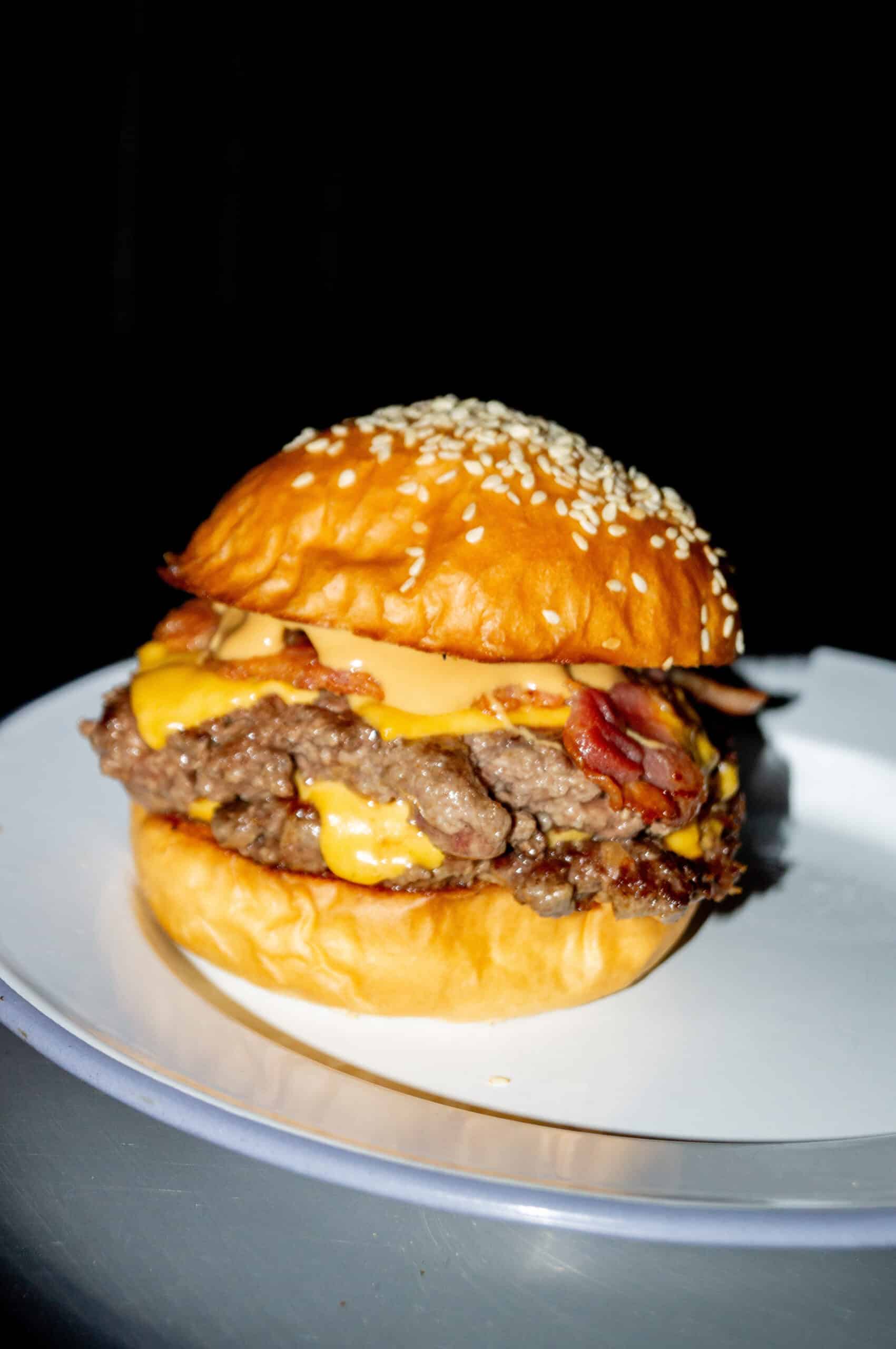 A double stacked cheeseburger with bacon on a sesame brioche bun